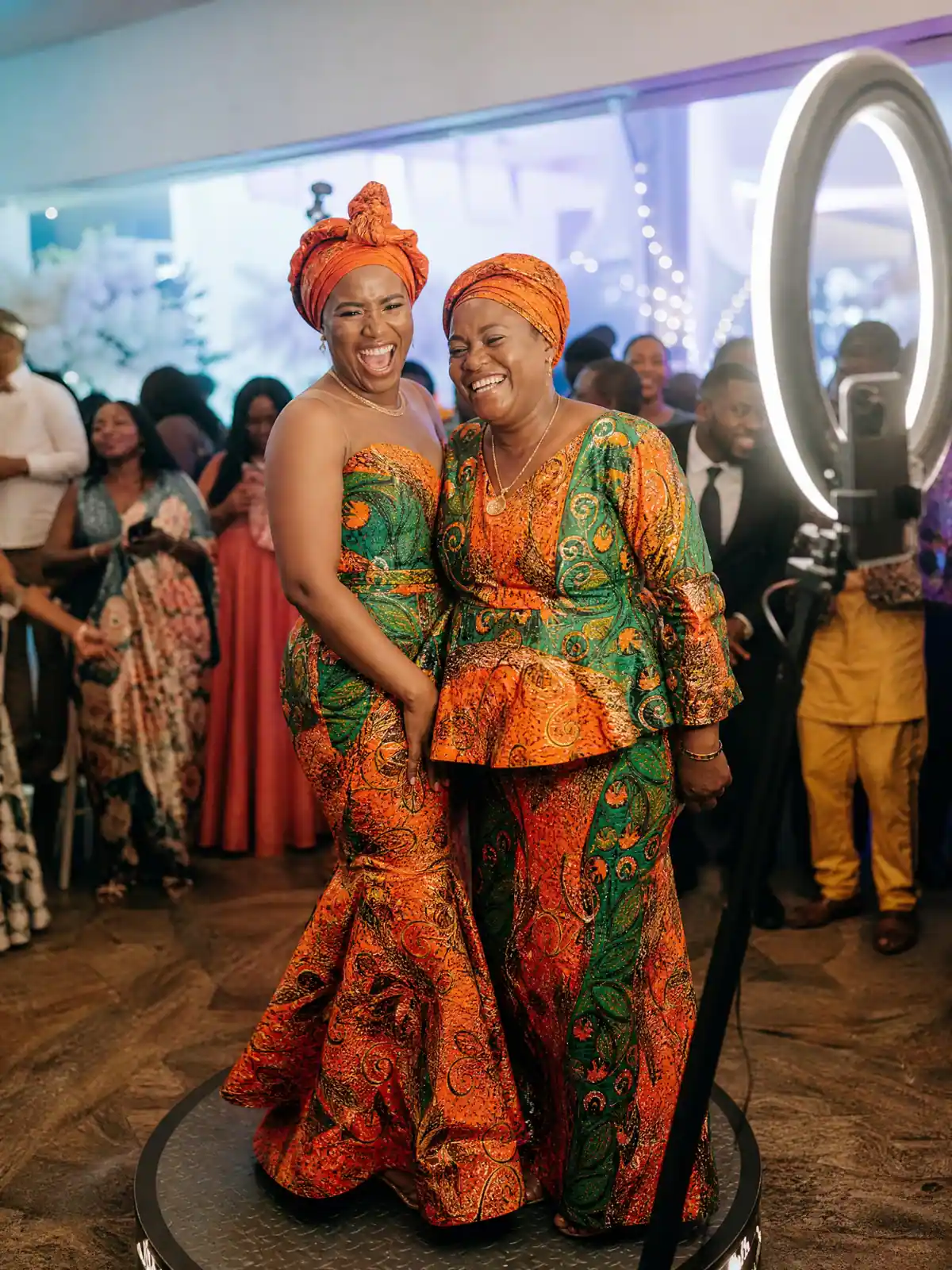 Bride and her mother in matching fabric laughing on the 360 platform at a Freetown traditional wedding