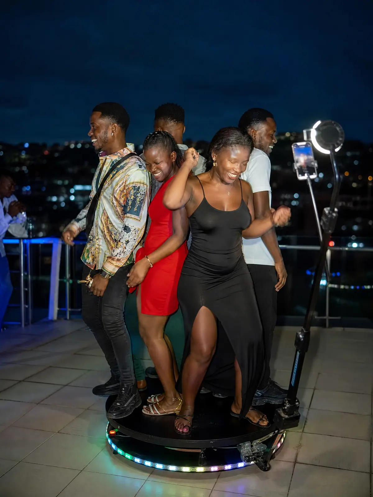 Friends dancing on a rooftop birthday party 360 booth in Freetown at night